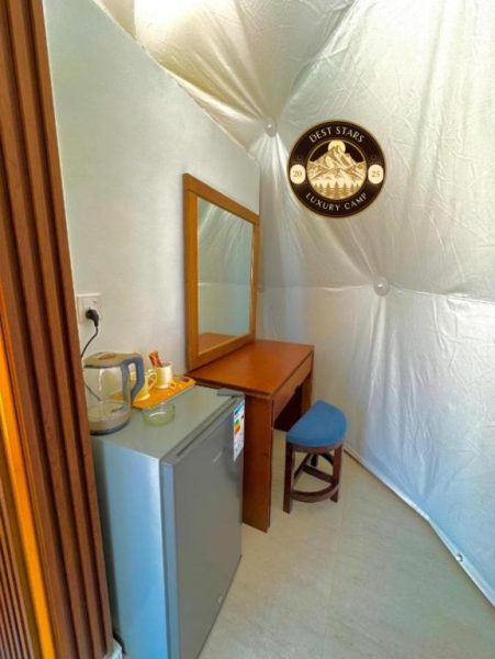 Interior de carpa con tocador, espejo y minibar en Dest Stars Luxury Camp