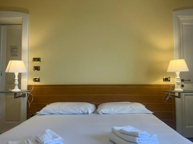 Habitación doble con cama matrimonial y mesitas con lámparas en Hotel Liberty