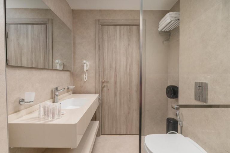 Baño moderno con lavabo empotrado, inodoro y amenities en el Golden Pillar Hotel
