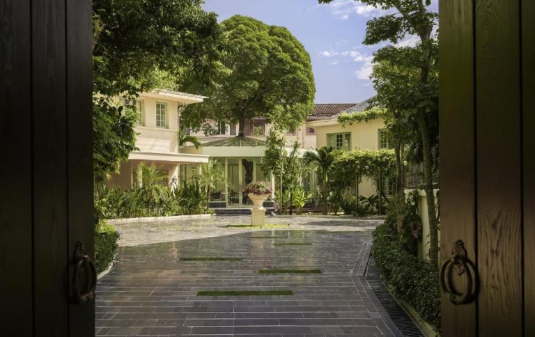Jardín tropical con entrada empedrada y villa colonial del President Maison Signature by M Village en Vietnam