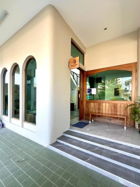 Entrada principal del Alleyhill Phuket Boutique con puerta de madera, ventanas arqueadas y escaleras de acceso