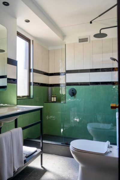Baño moderno con azulejos verdes y ducha de lluvia en Hotel Director Vitacura