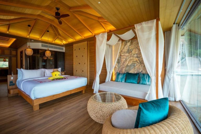 Habitación de lujo con dosel blanco, cama king y techo de madera en SINAE Phuket Luxury Hotel