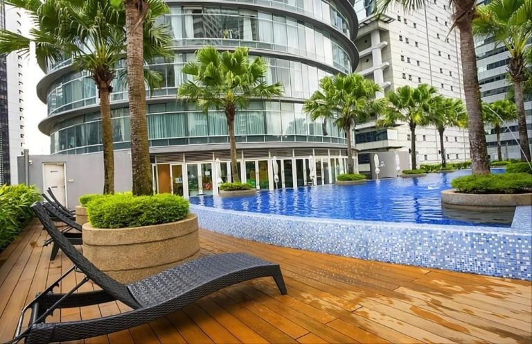 Piscina exterior con tumbonas y palmeras tropicales en Vortex Suites KLCC by Chia, Kuala Lumpur