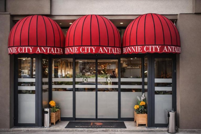 Entrada principal del Bonnie City Hotel Antalya con toldos rojos y plantas decorativas