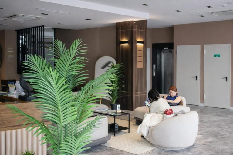 Zona de recepción y lobby del Bonnie City Hotel con sofás blancos y plantas tropicales decorativas