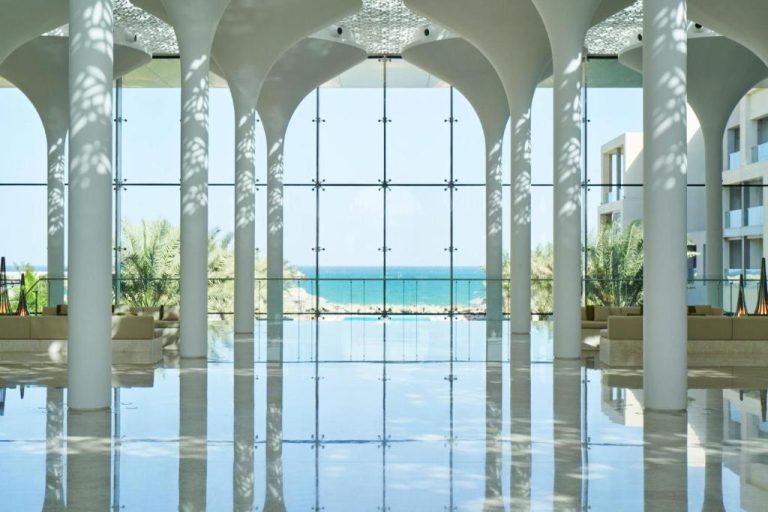 Luminoso lobby con arcos blancos y vista panorámica al mar en el Kempinski Hotel Muscat