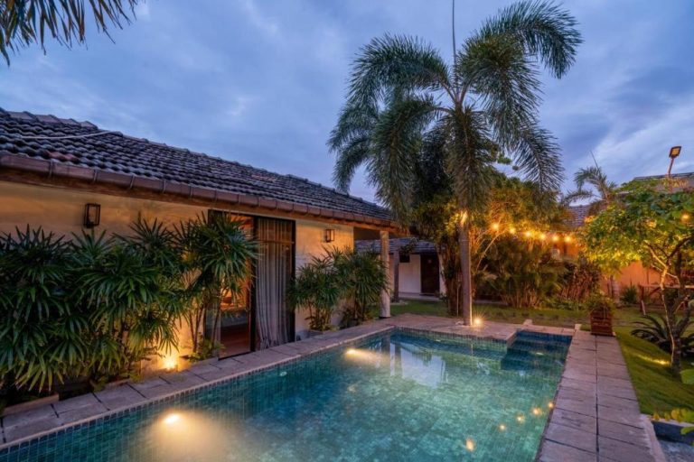 Piscina privada iluminada al atardecer en The Barns Villas and Restaurant rodeada de palmeras