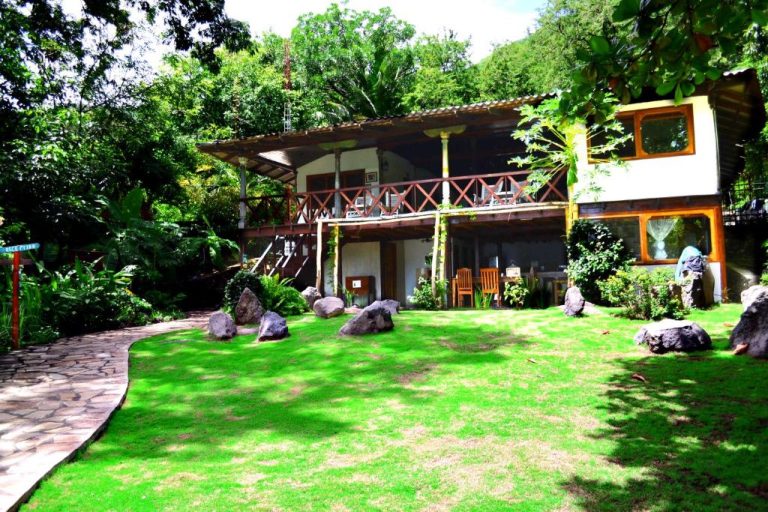 Jardín tropical con césped y bungalow de madera en Laguna Beach Club rodeado de vegetación