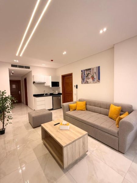 Sala de estar moderna con sofá gris y cojines amarillos en Zones Residence Maadi con cocina integrada
