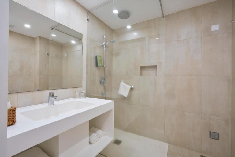 Baño moderno con ducha de lluvia y lavabo blanco en el Caloura Hotel Resort
