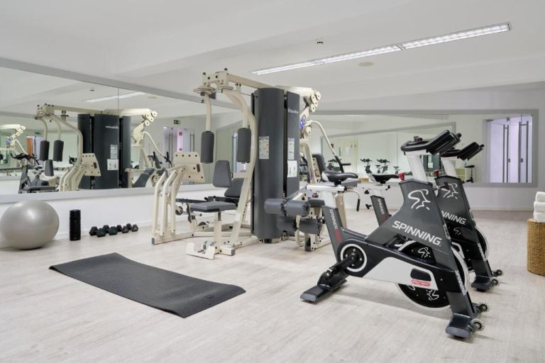 Gimnasio equipado con bicicletas de spinning y máquinas de musculación en Caloura Hotel Resort