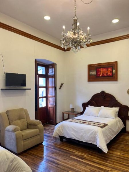 Habitación elegante con cama matrimonial de madera tallada y lámpara de araña en Rossa Mia Hotel Boutique
