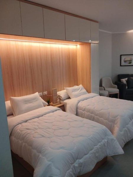 Habitación doble con dos camas individuales y cabecero iluminado en madera en el Resort Skandic