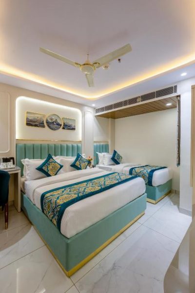 Habitación twin de lujo con cabeceros turquesa y decoración elegante en The Western Grand Hotel cerca de Nueva Delhi