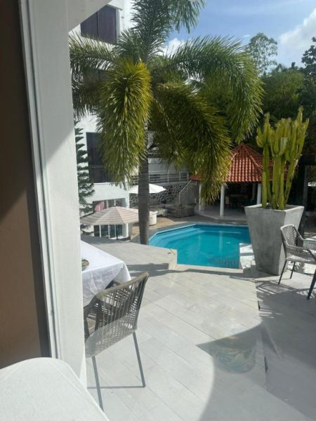 Piscina exterior con terraza y palmeras del Onyx Luxury RD, área de descanso con sillas y gazebo