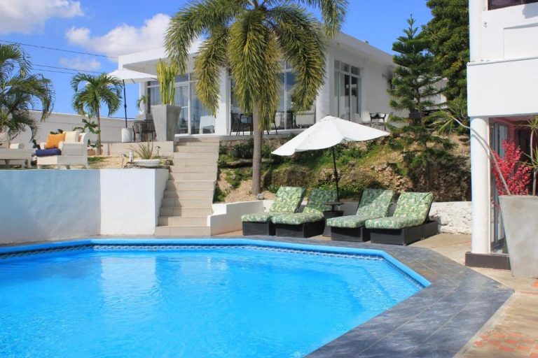 Piscina exterior azul con tumbonas y sombrilla del Onyx Luxury RD rodeada de palmeras