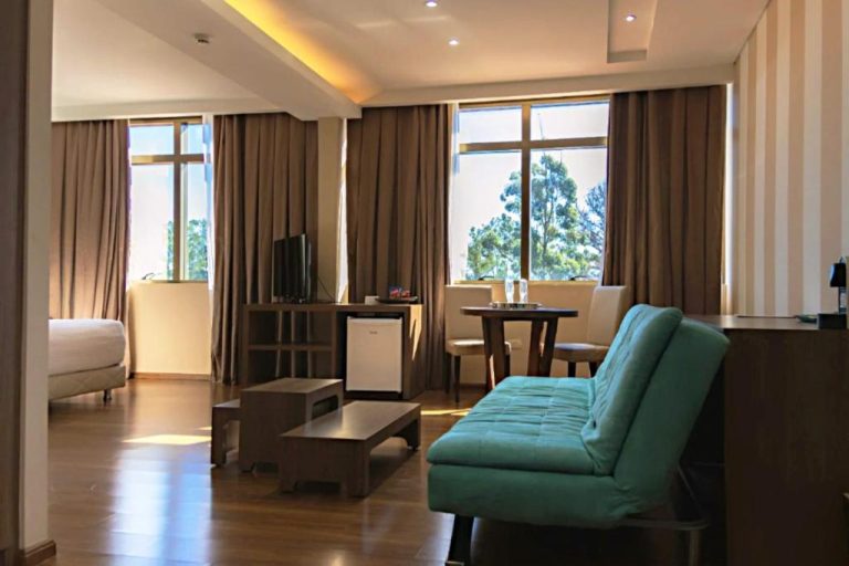 Suite amplia del Awa Resort Hotel con sofá turquesa, sala de estar y ventanales con vista a jardines