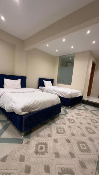 Habitación doble con dos camas tapizadas en azul y ropa de cama blanca en Pyramids View Top