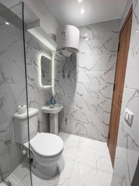 Baño moderno con revestimiento de mármol blanco, ducha y sanitarios en Pyramids View Top