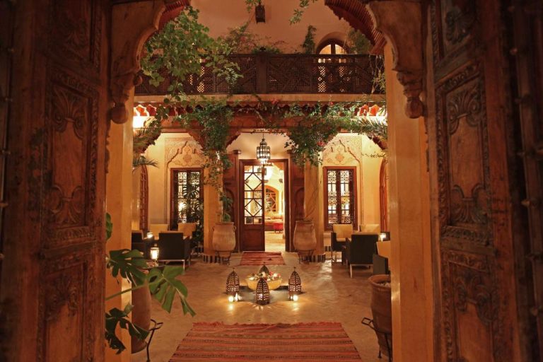 Patio interior iluminado del La Maison Arabe Hotel con arcos árabes, linternas y vegetación en Marrakech