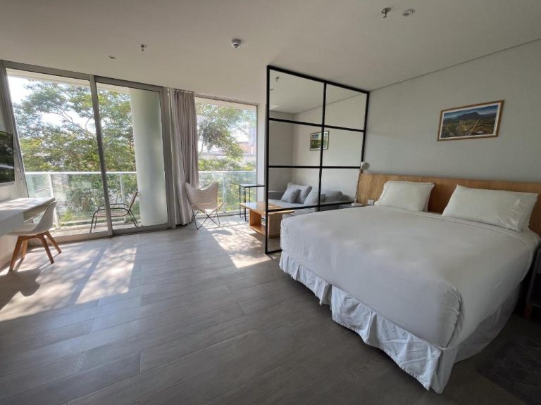 Habitación doble con cama king, suelo de madera y balcón con vistas verdes en Solara Hotel Boutique