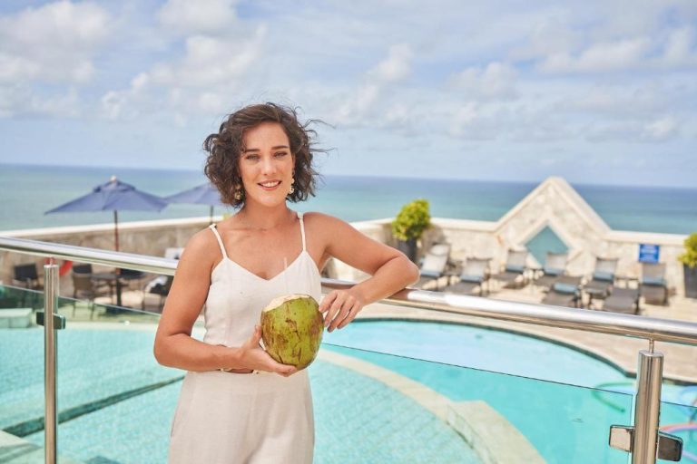 Mujer con coco fresco en la terraza piscina del Hotel Atlante Plaza con vistas al mar