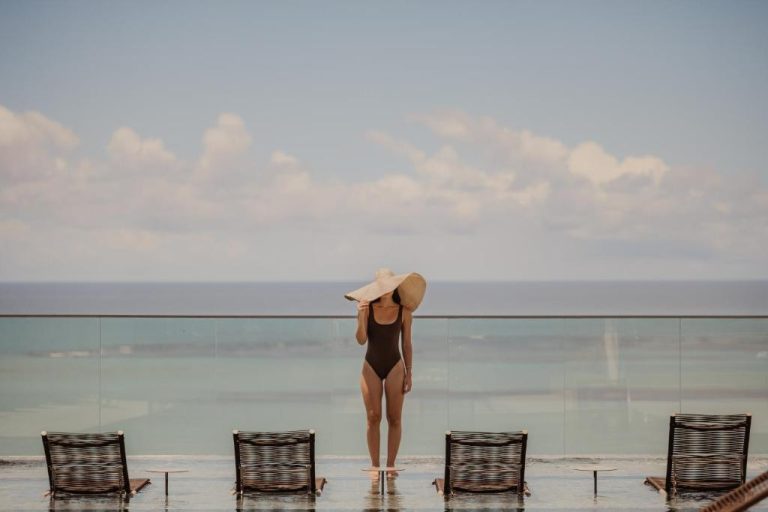Mujer junto a la piscina infinita con vistas al mar turquesa del Venti Hotel by Brisa Hotéis