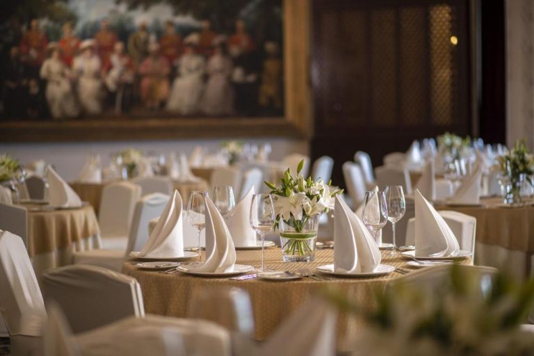 Salón de banquetes elegante con mesas decoradas y flores blancas en The Imperial New Delhi
