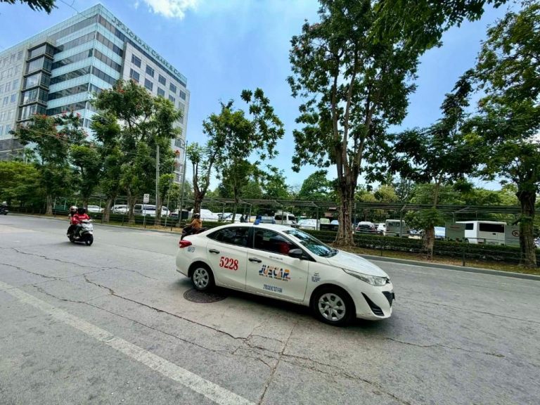 Taxi blanco frente al edificio JP Morgan en Cebu IT Park, zona de alojamiento del Cozy Studio