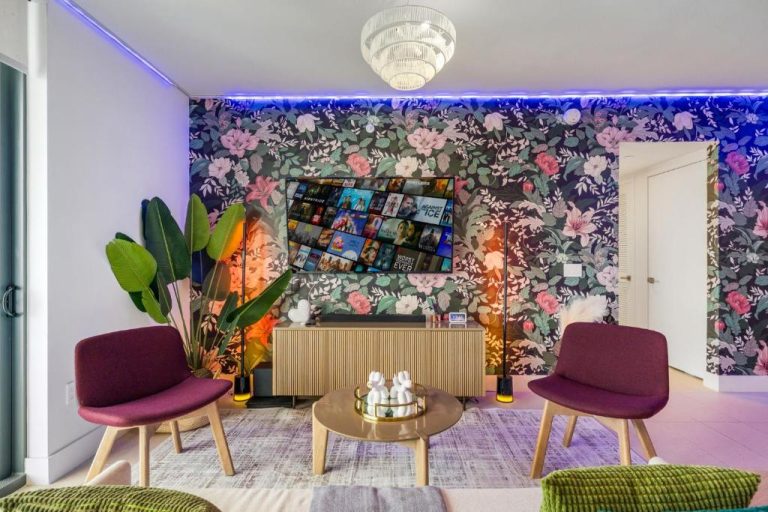 Sala de estar con papel tapiz floral, sillones burdeos y TV en apartamento Stunning Lux 2 Bed 2 Bath