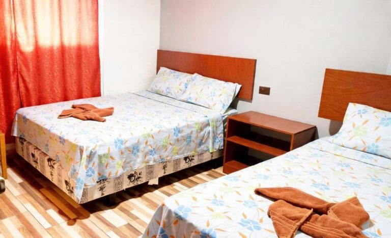 Habitación doble con dos camas y cortinas rojas en Hotel Girasol, suelo de parquet y mesita de noche