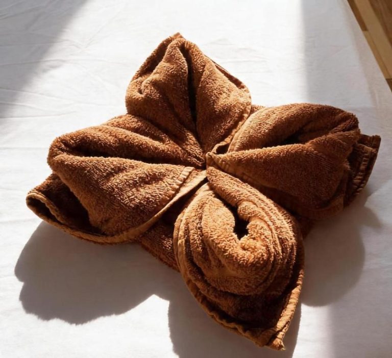 Toalla decorativa doblada en forma de flor en habitación del Hotel Girasol