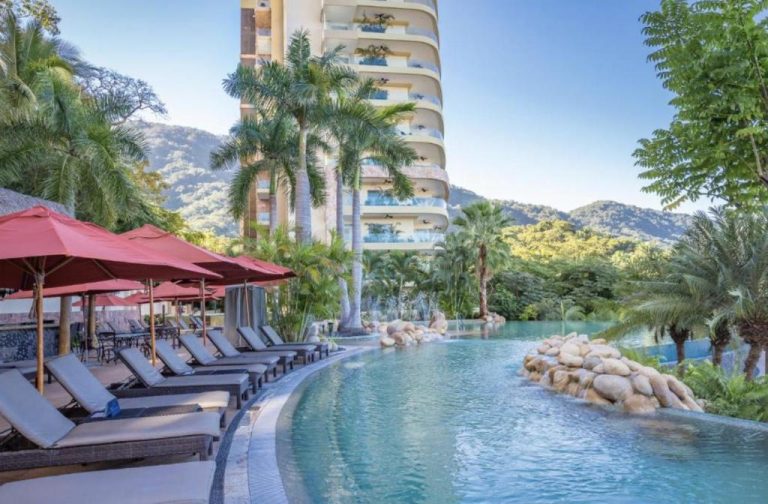 Piscina infinity con camastros y palmeras del Garza Blanca Preserve Resort & Spa en Puerto Vallarta