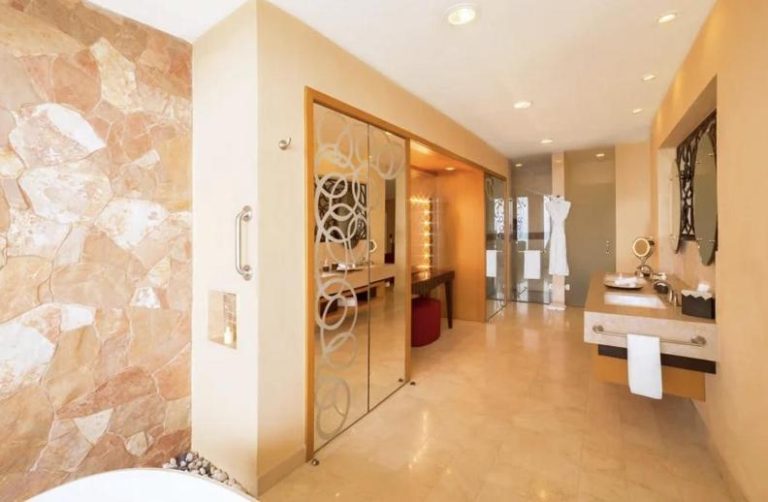 Baño de lujo con pared de piedra natural y cabina de cristal en Garza Blanca Preserve Resort & Spa Puerto Vallarta