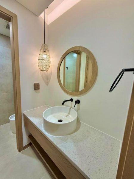 Baño moderno con lavabo redondo sobre encimera de mármol y espejo circular en Minh Anh Hotel
