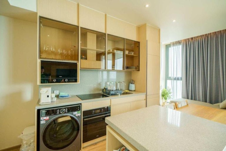 Cocina moderna equipada con lavadora y gabinetes de madera en Luxury 2BR Sea View Apartment