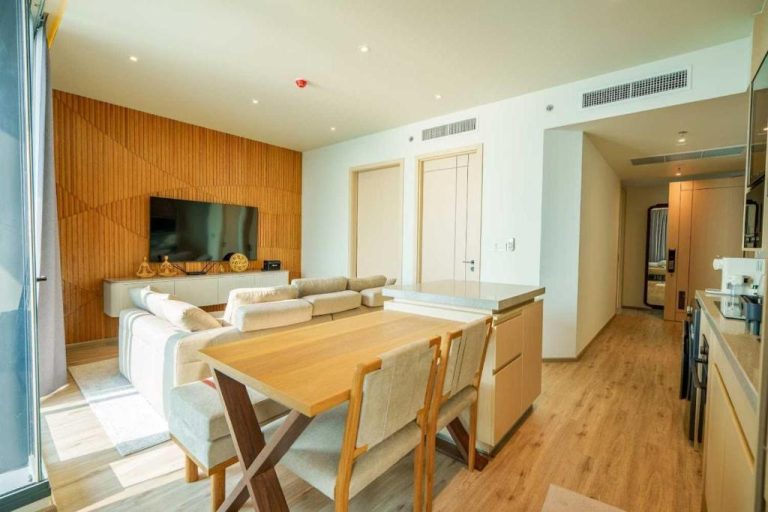 Salón comedor moderno con mesa de madera y cocina abierta en Luxury 2BR Sea View Apartment