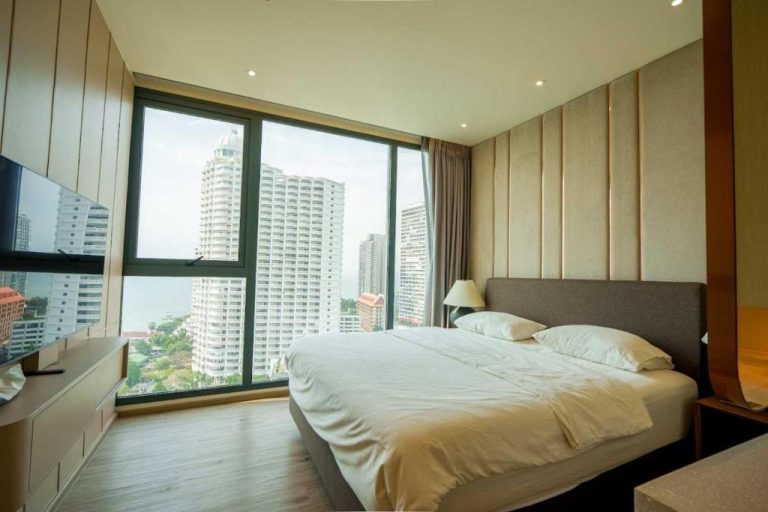 Habitación de lujo con cama doble y ventanales con vista al mar y rascacielos en Luxury 2BR Sea View Apartment