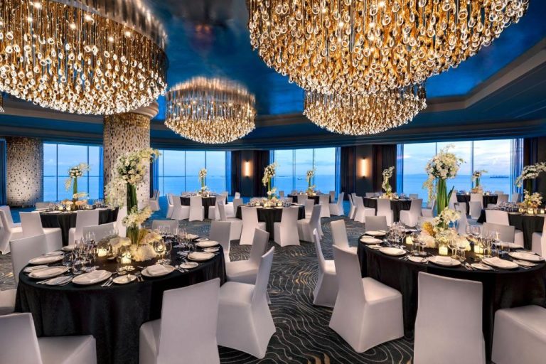 Salón de eventos con lujosas arañas de cristal doradas y vistas al mar en NUSTAR Hotel Cebu