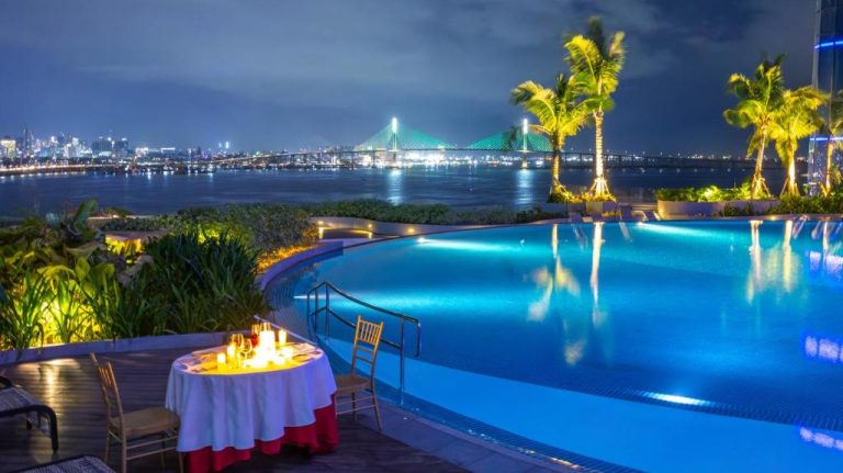 Piscina infinita con cena romántica a la luz de velas y vista al puente iluminado en NUSTAR Hotel Cebu