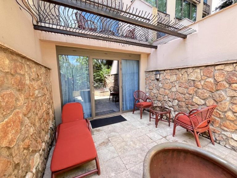 Terraza privada con tumbonas y sillas de ratán del Nairobi Serena Hotel, con paredes de piedra