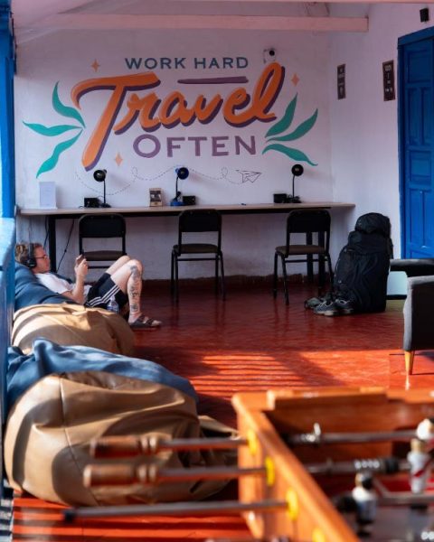 Sala común con zona de trabajo y mural 'Work Hard Travel Often' en Way Kap Hostel Cusco