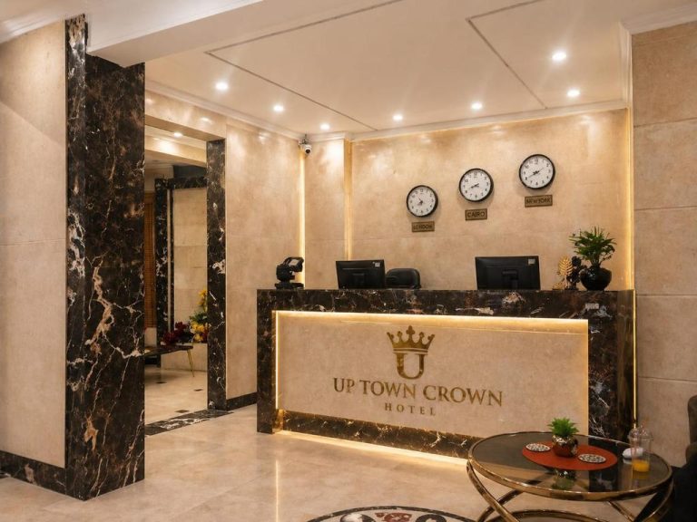 Recepción elegante con mostrador de mármol y relojes mundiales en Up Town Crown Hotel