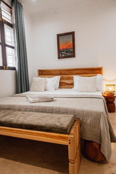 Habitación doble con cama de madera y decoración rústica en Nyumbani Stonetown, Zanzíbar