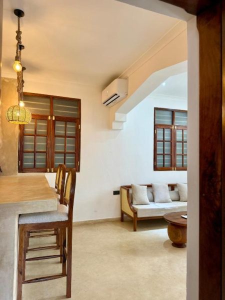 Sala de estar y zona de comedor con decoración rústica y aire acondicionado en Nyumbani Stonetown
