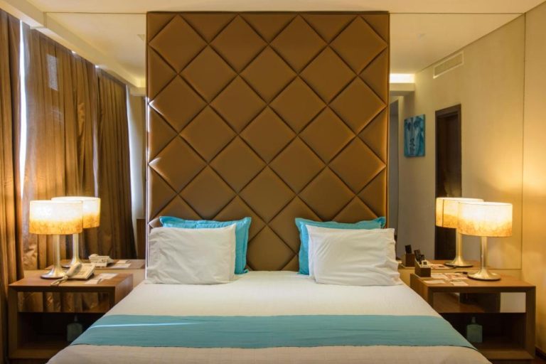 Habitación de lujo con gran cabecero de cuero acolchado y cojines turquesa en Awa Resort Hotel