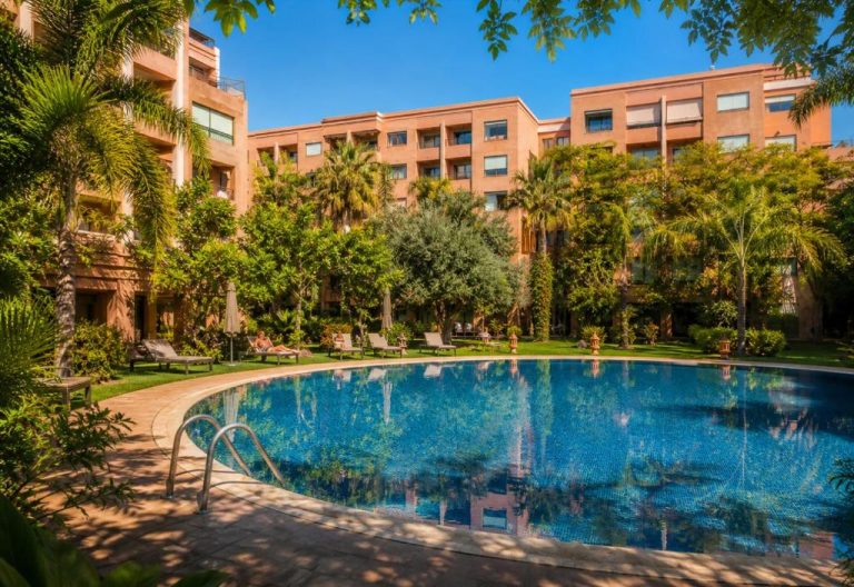 Piscina exterior rodeada de jardines tropicales en Babylone Appart & Pool Hivernage en Marrakech