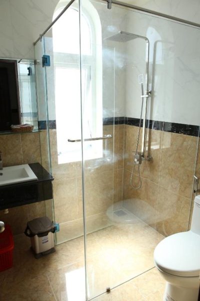 Baño moderno con ducha de cristal y sanitarios en mármol del Quang Trung Phu Quoc Hotel