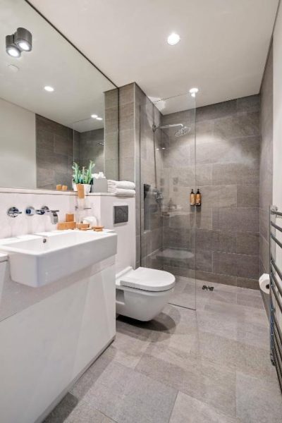 Baño moderno con ducha de lluvia y sanitario suspendido en el Wren Urban Nest